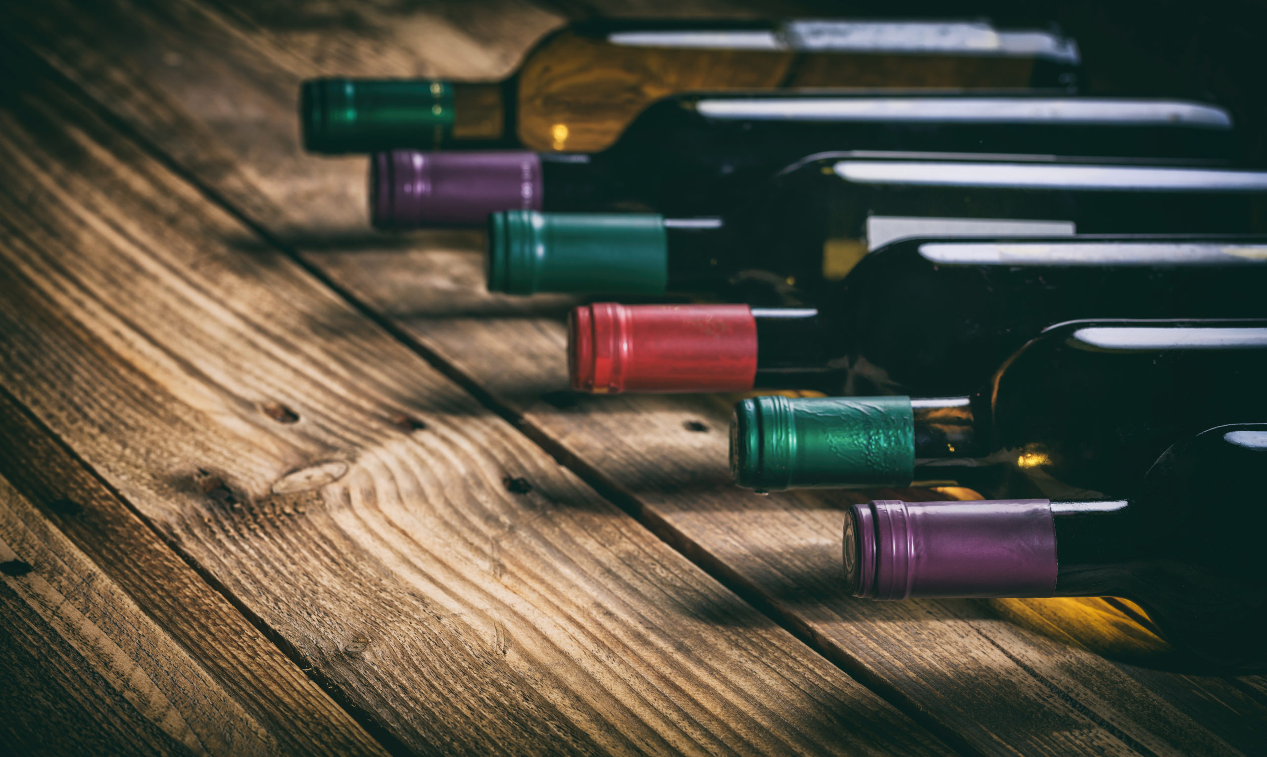 Wine bottles collection on a wooden table, dark background, copy space